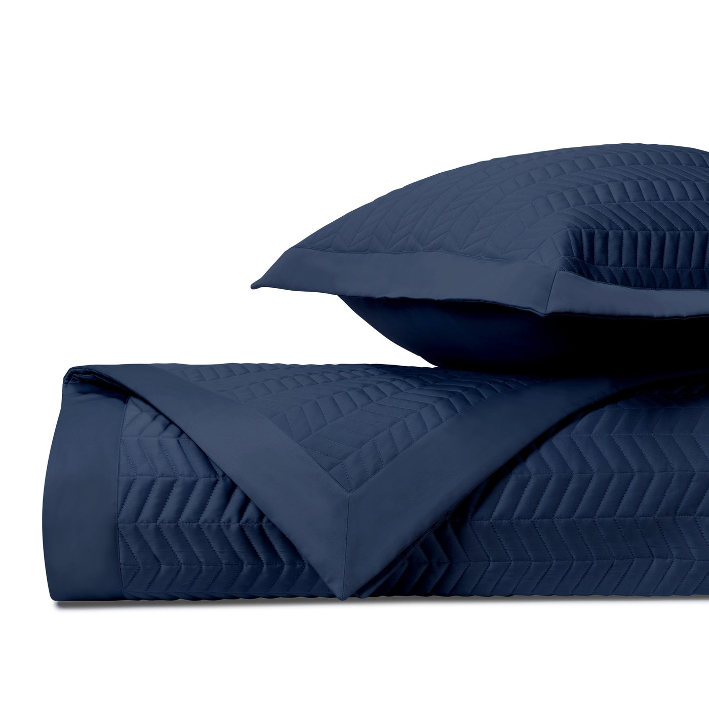 Navy blue quilted chevron-pattern coverlet and sham, folded to show texture detail.
