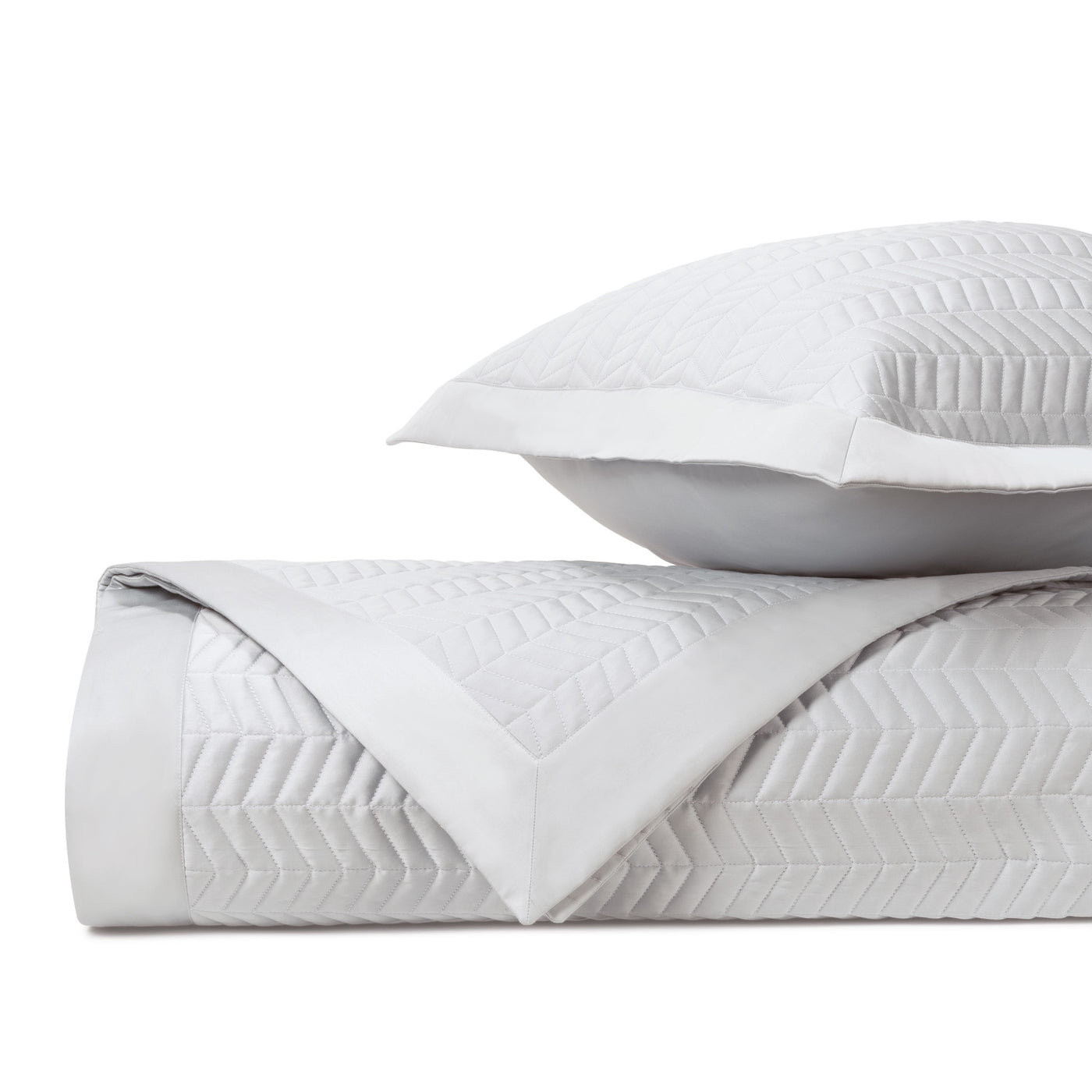 Close-up of white quilted cotton with raised herringbone texture and border detail.