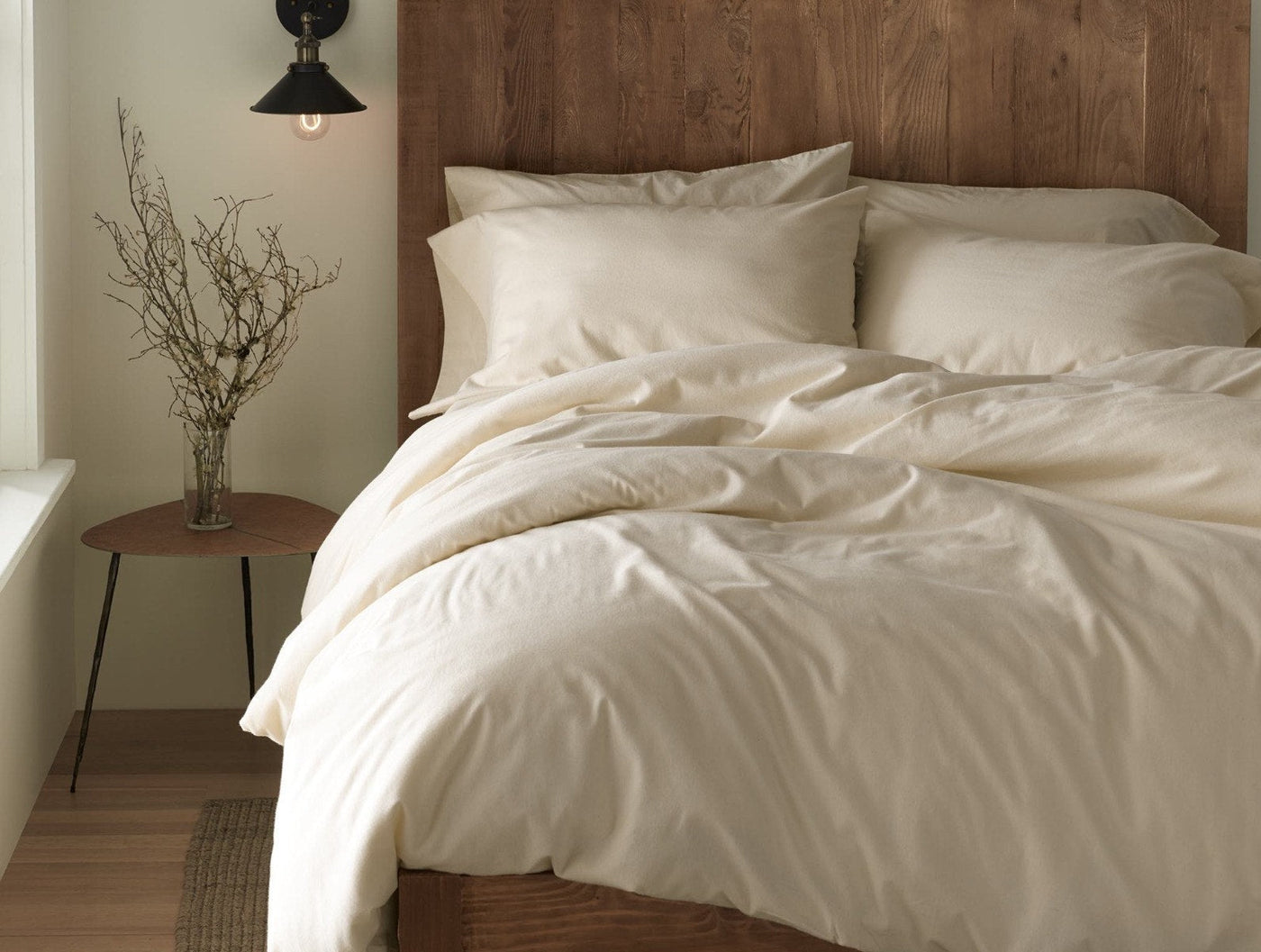 Ivory flannel bedding styled on a bed with wood headboard, warm neutral bedroom setting.