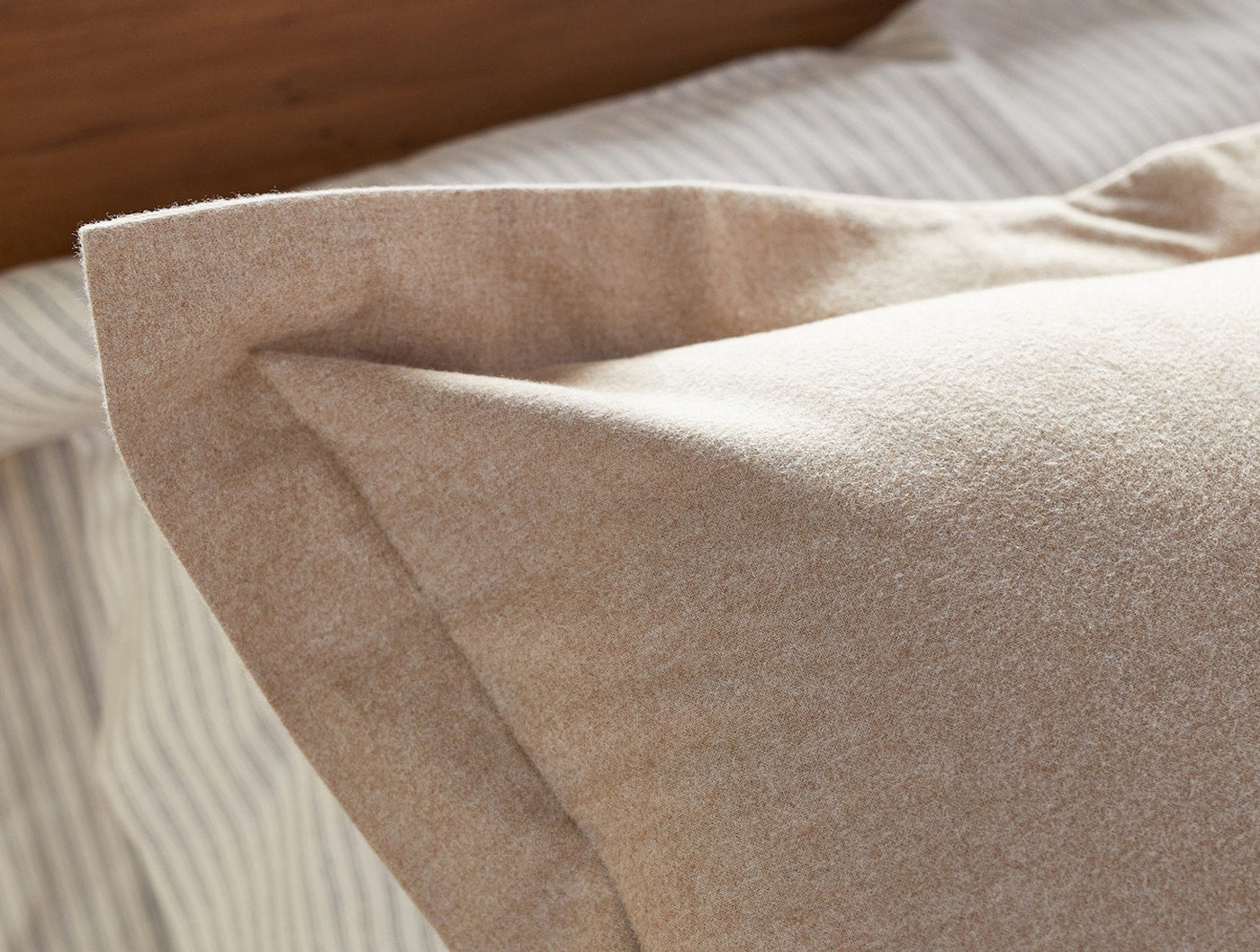 Close-up of Coyuchi Cloud Brushed Flannel sham edge, showing soft brushed texture in warm sand.