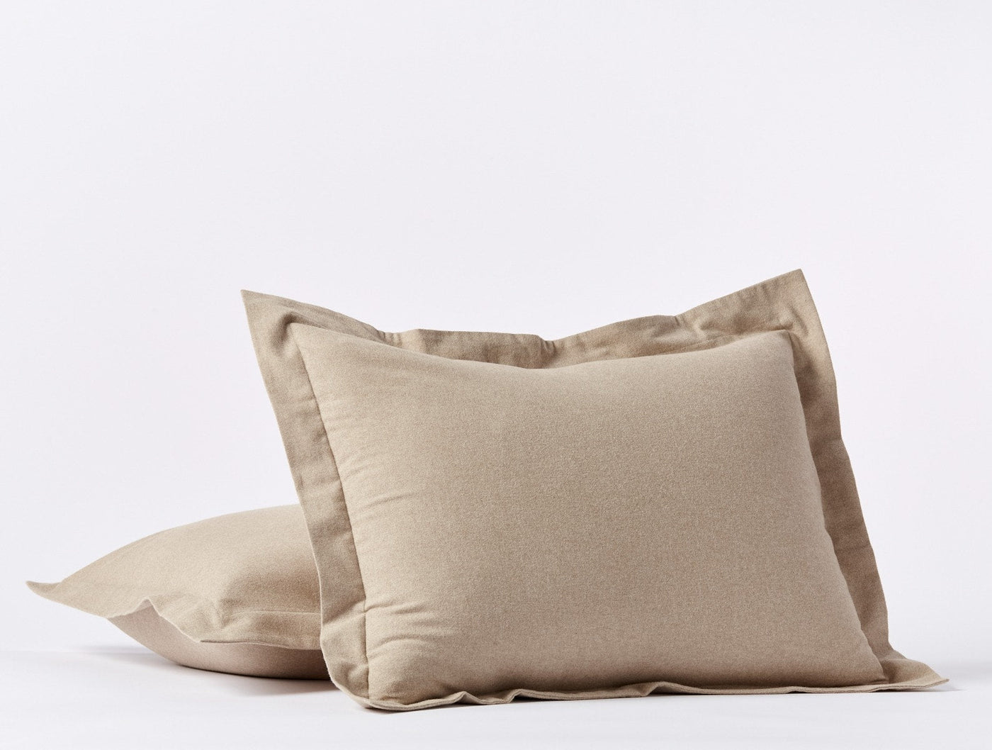 Close-up of two stacked Coyuchi Cloud Brushed Flannel shams in warm taupe with flange trim.