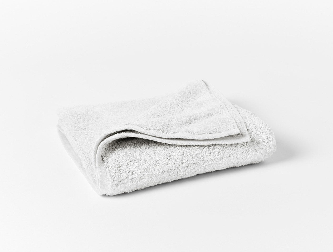 Folded white terry hand towel showing plush loop texture and clean hem detail.