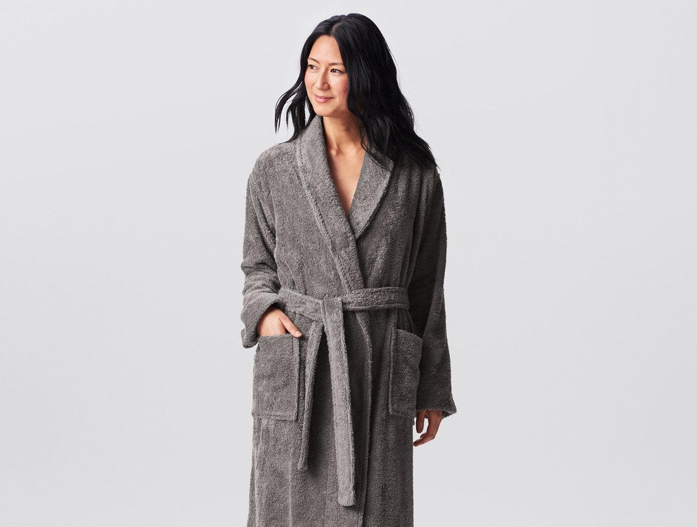 Model wearing Coyuchi Cloud Loom robe in charcoal grey terry, belted, full length.