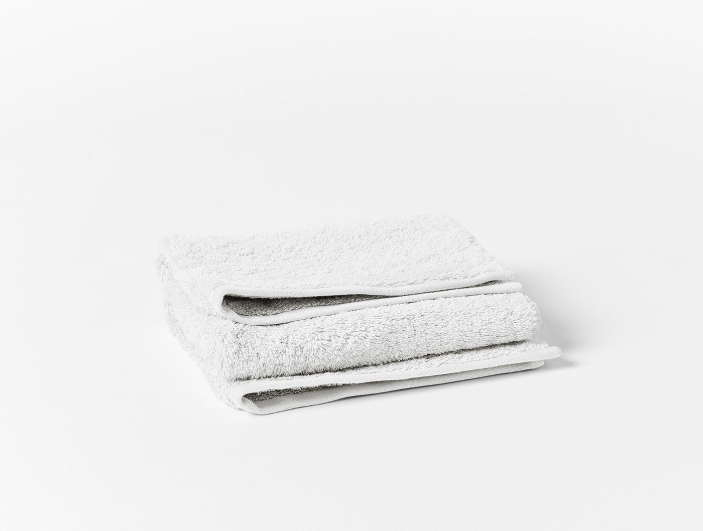 Two folded white terry towels stacked against a white background.