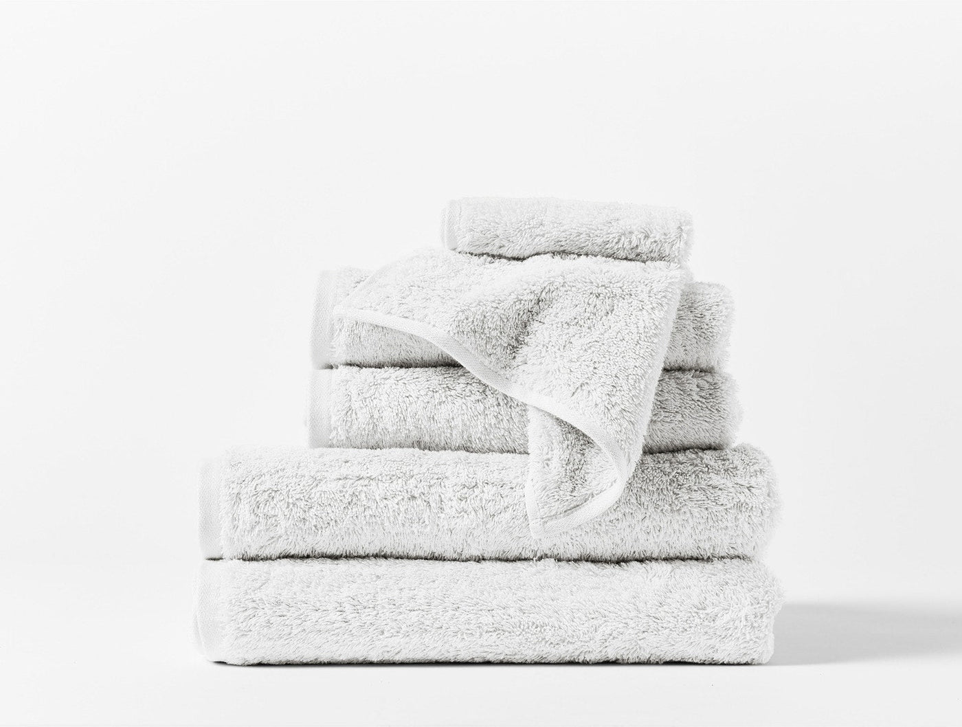 Coyuchi Cloud Loom 6-piece towel set in white, stacked neatly against white background.
