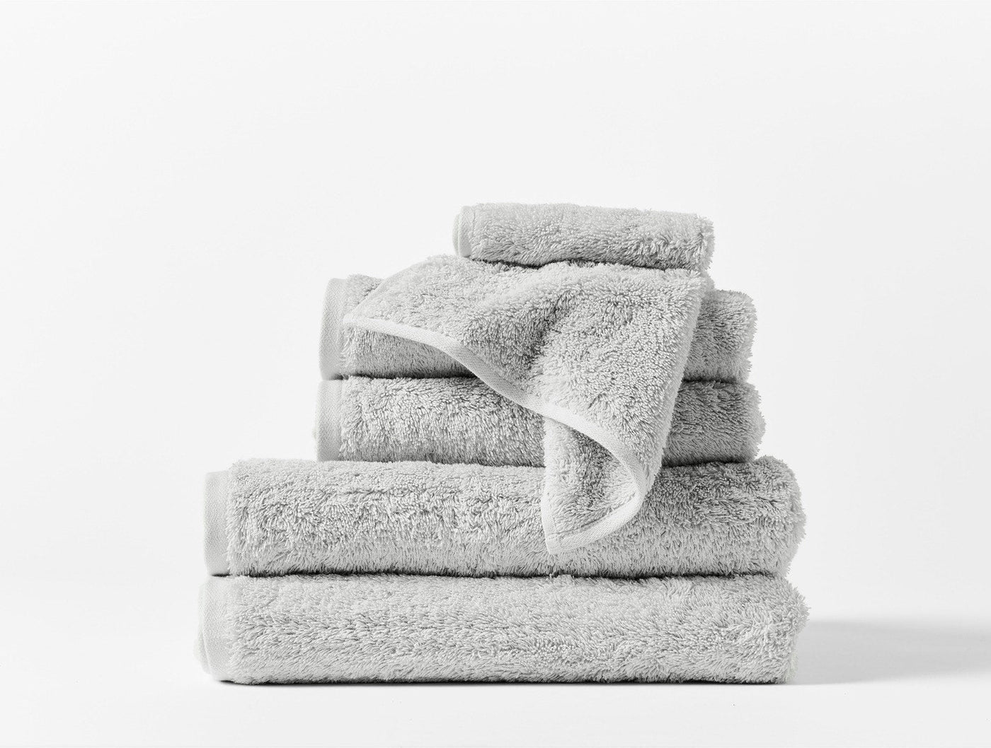 Stacked silver Coyuchi Cloud Loom towels in assorted sizes on white background.