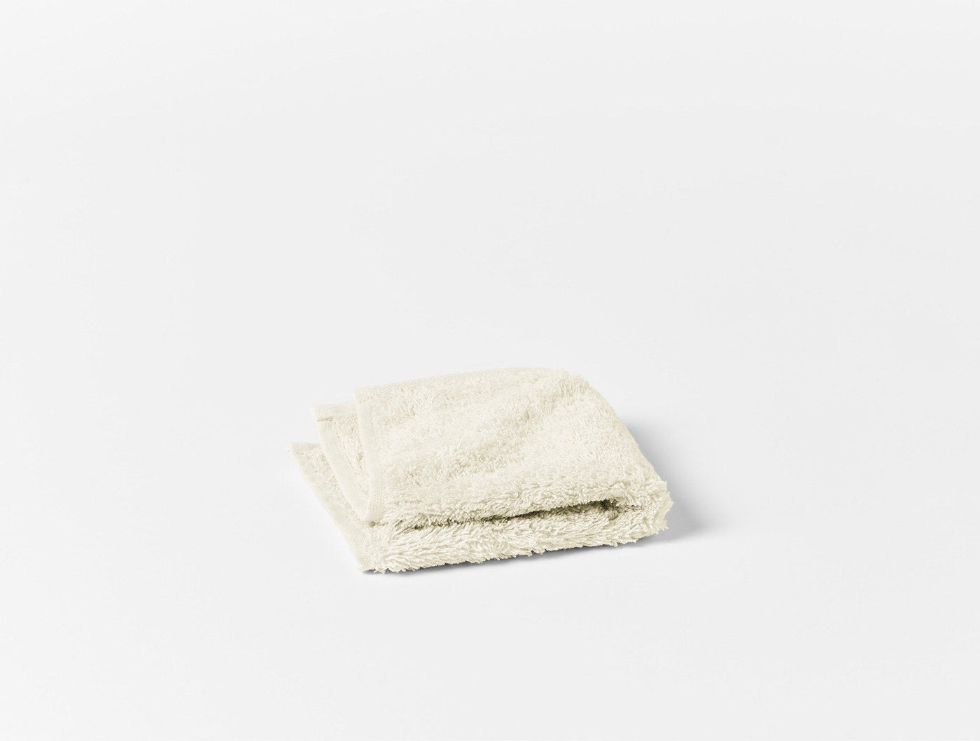 Coyuchi Cloud Loom ivory terry washcloth folded, showing plush looped texture.