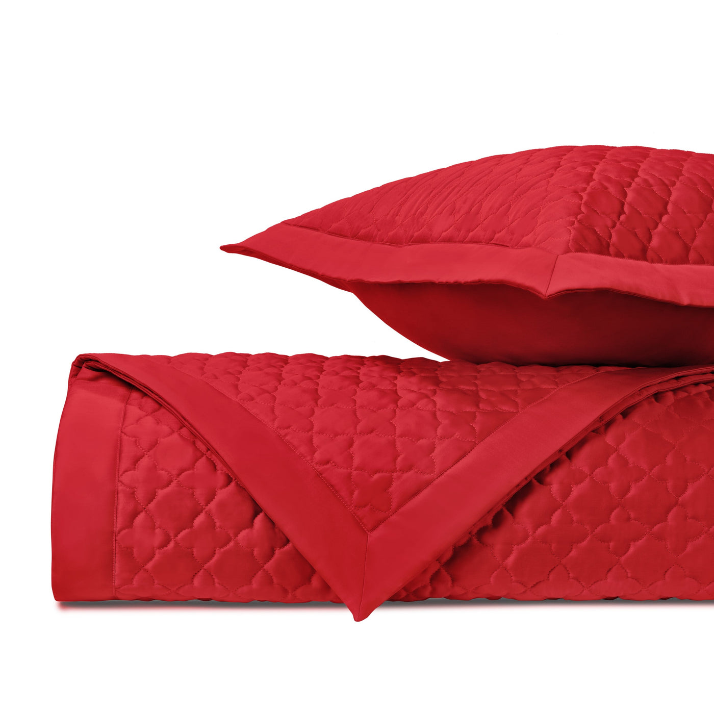 Crimson quilted clover-pattern texture on folded coverlet and sham.