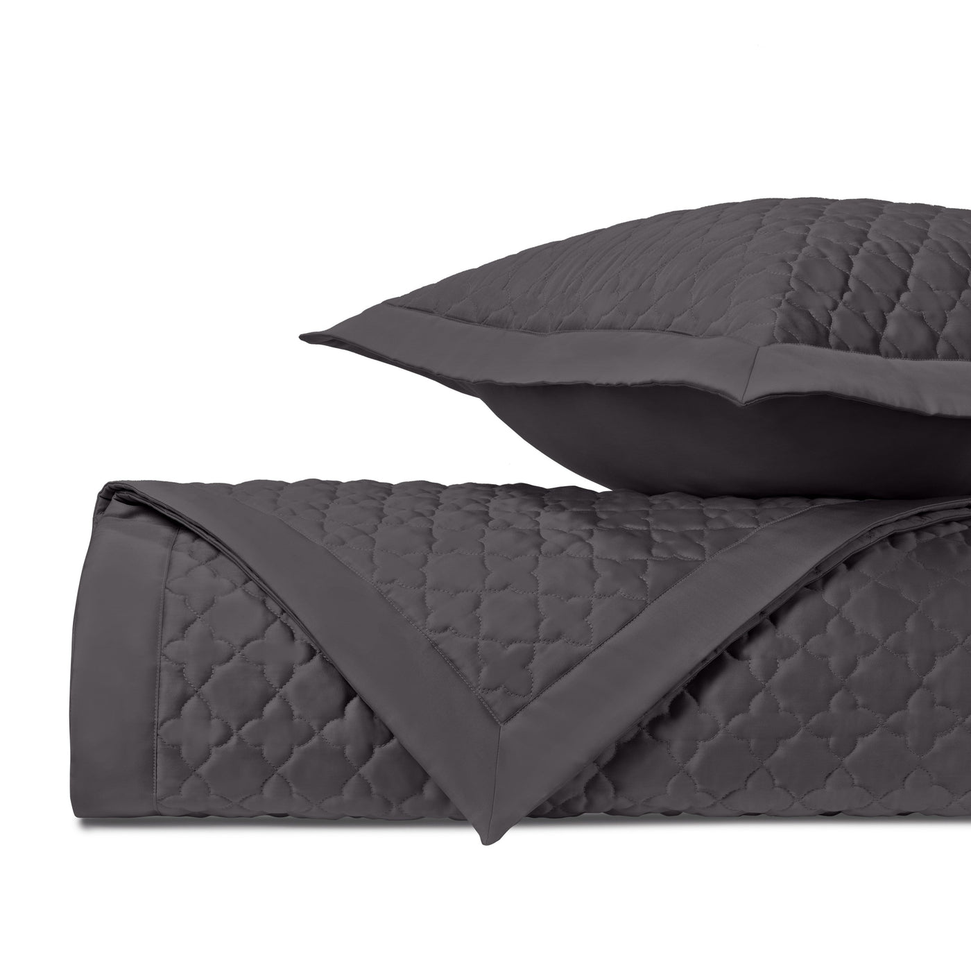 Close-up of charcoal quilted clover diamond pattern on folded coverlet with matching sham.