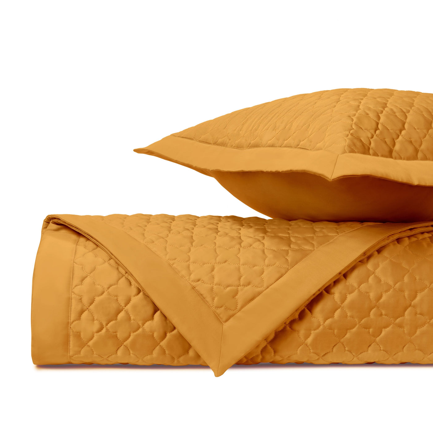 Close-up of marigold quilted clover-pattern coverlet and sham, folded and stacked.