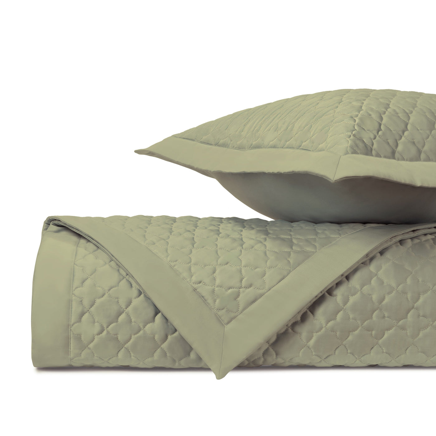 Sage green quilted texture close-up with diamond lattice stitching on folded coverlet and sham.