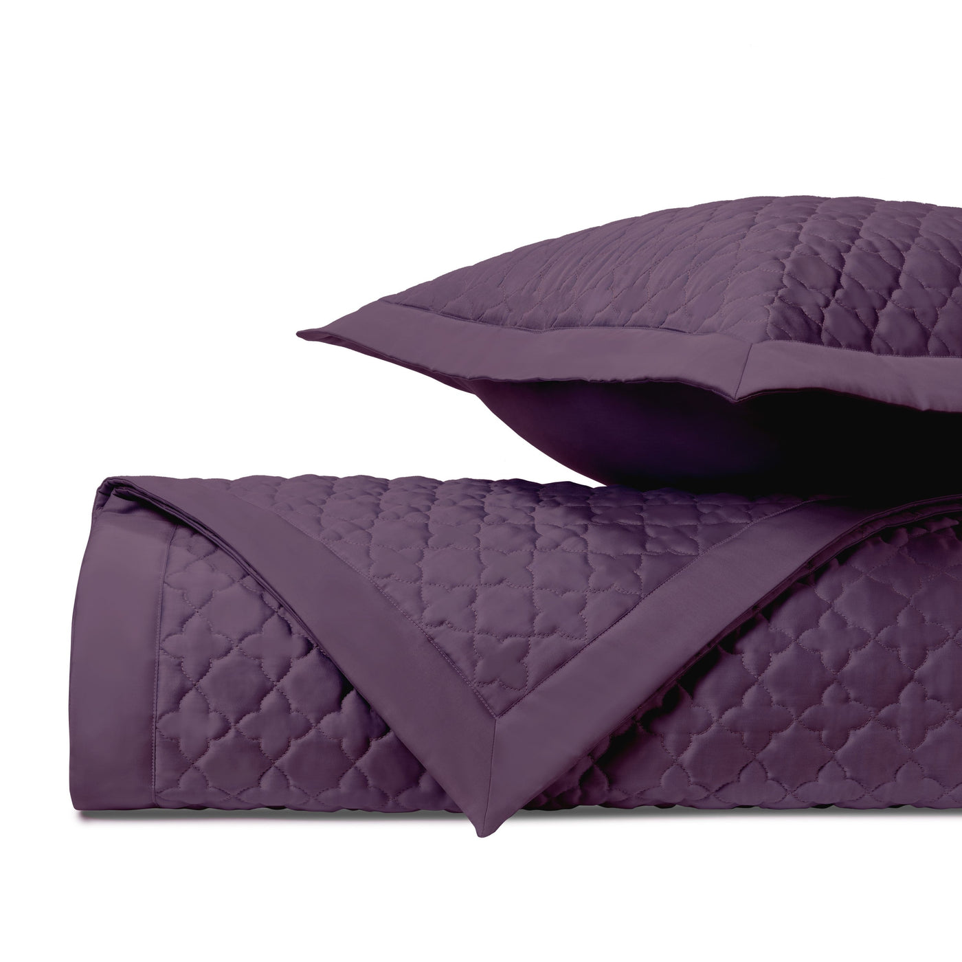 Close-up of amethyst quilted clover-pattern fabric with flanged sham and rolled coverlet edge.