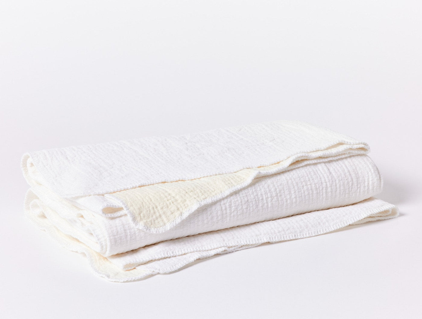 Coyuchi Cozy Cotton blanket in white, folded to show crinkled muslin texture.