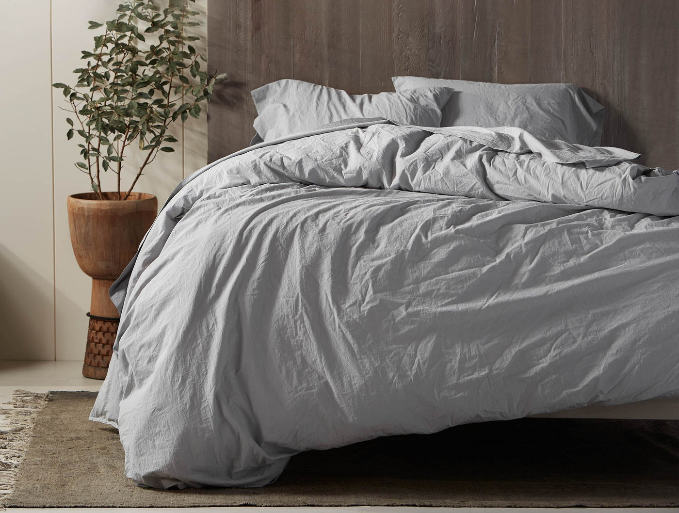 Coyuchi silver-grey crinkled percale duvet draped on bed in natural bedroom setting.