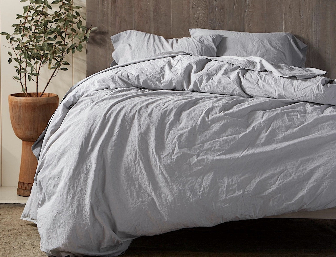 Close-up of Coyuchi Crinkled Percale sham in silver-grey, styled on a bed with relaxed, rumpled texture.