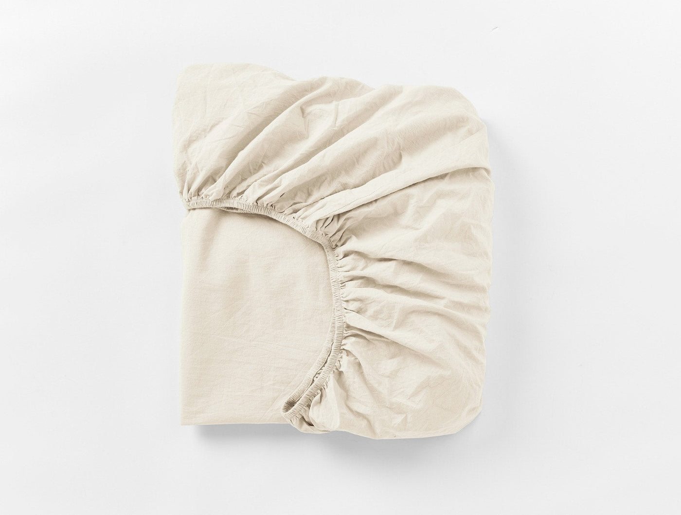 Folded ivory fitted sheet showing elasticized corners and crinkled percale texture.
