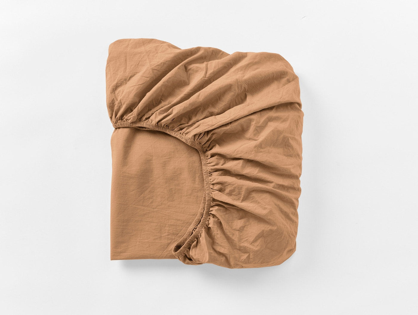 Coyuchi Crinkled Percale fitted sheet in caramel, folded to show elasticated corners.