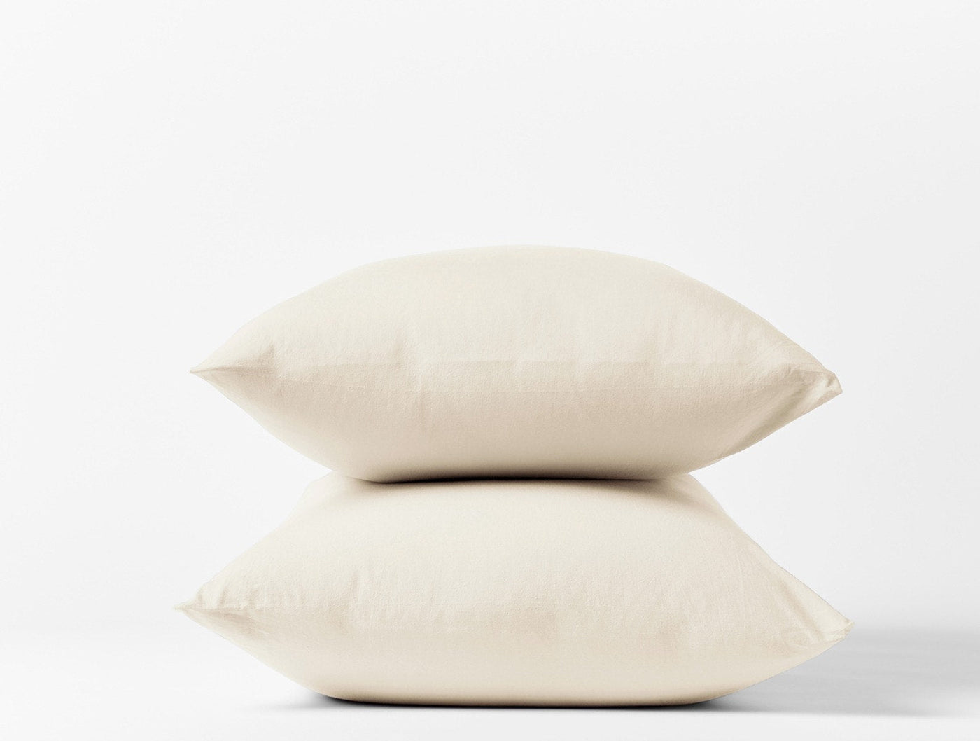 Two stacked ivory Coyuchi Crinkled Percale pillowcases against a white background.