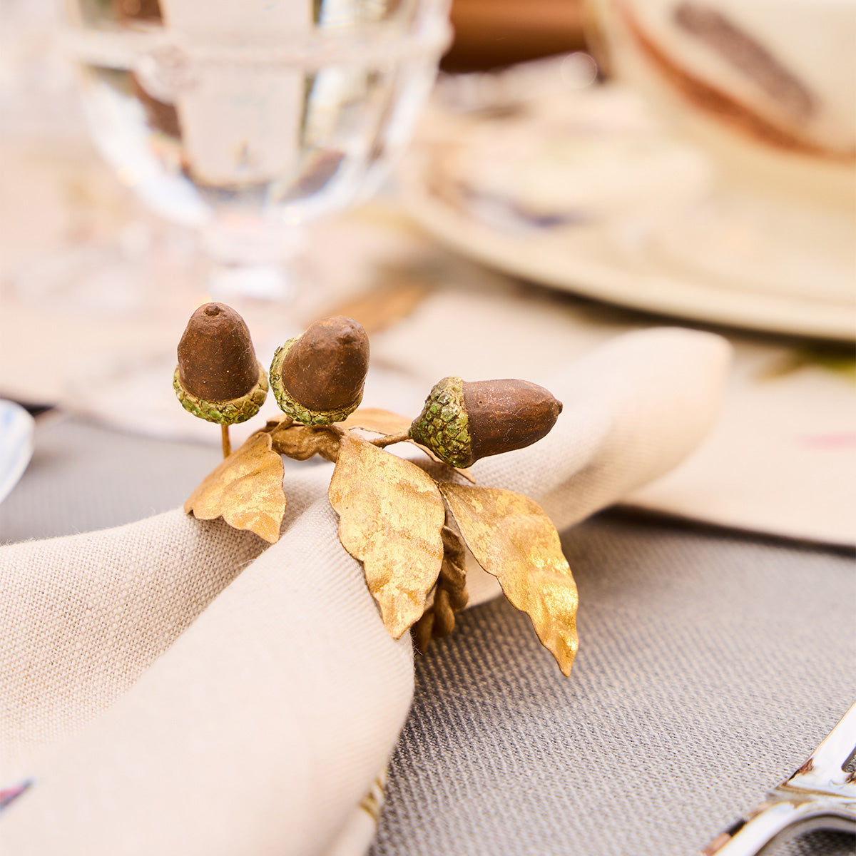 Close-up of an acorn napkin ring on a cream linen napkin at a table setting