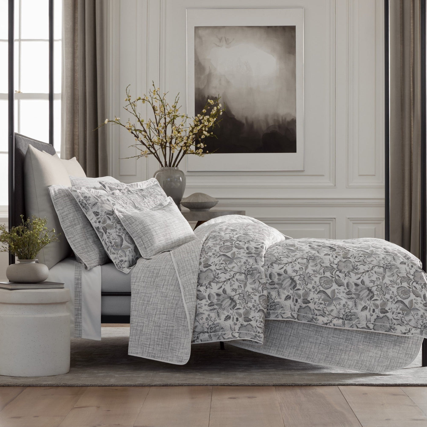 Silver grey floral quilted bedding set styled on a bed in a neutral bedroom.