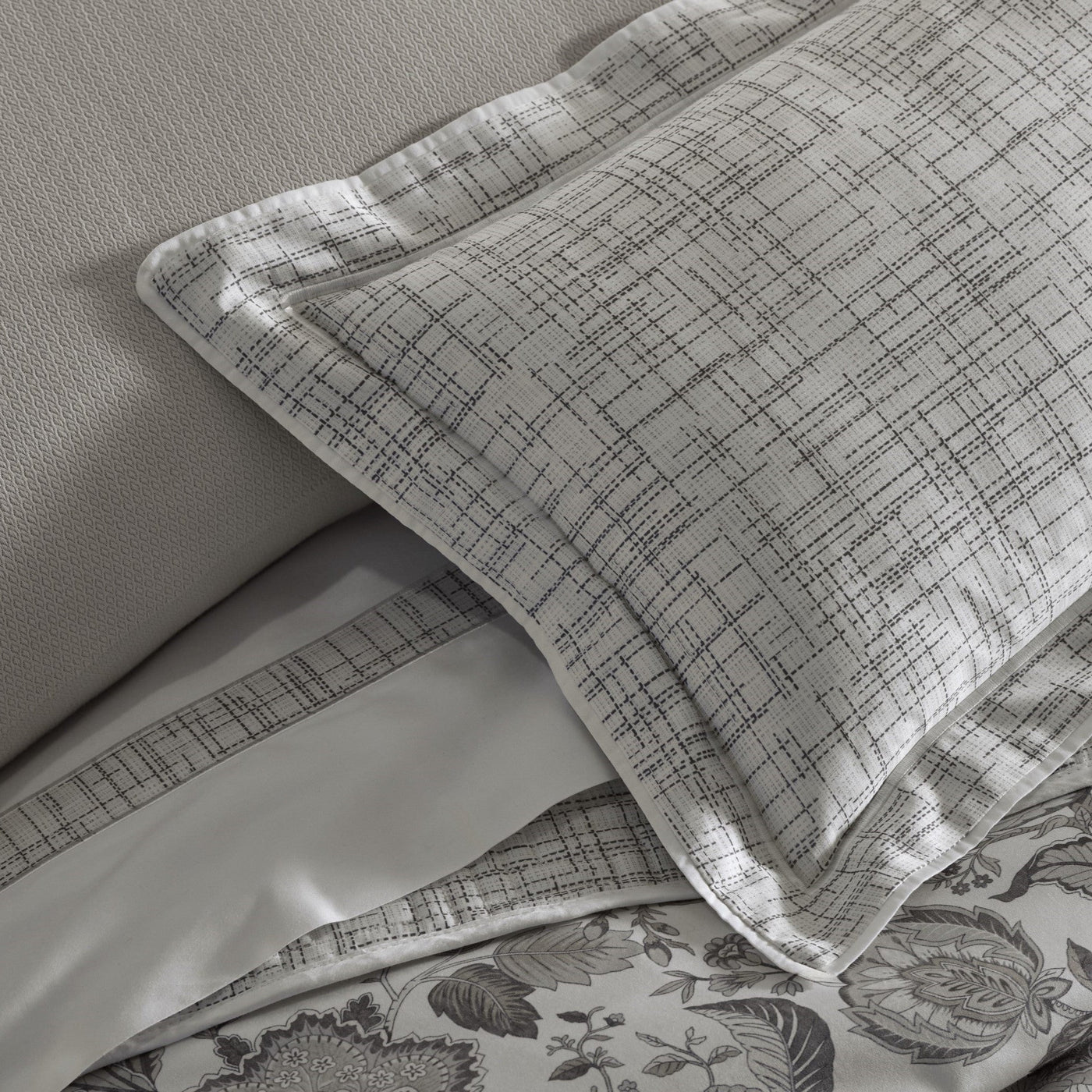 Close-up of Home Treasures Daphne pillow sham with grey crosshatch weave pattern and white trim.