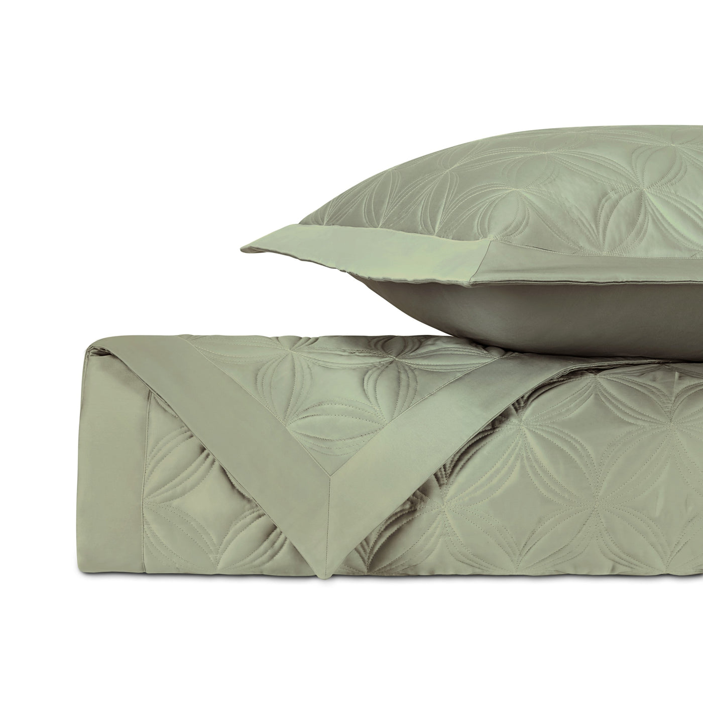 Sage green quilted coverlet folded with matching euro sham, floral medallion pattern visible.