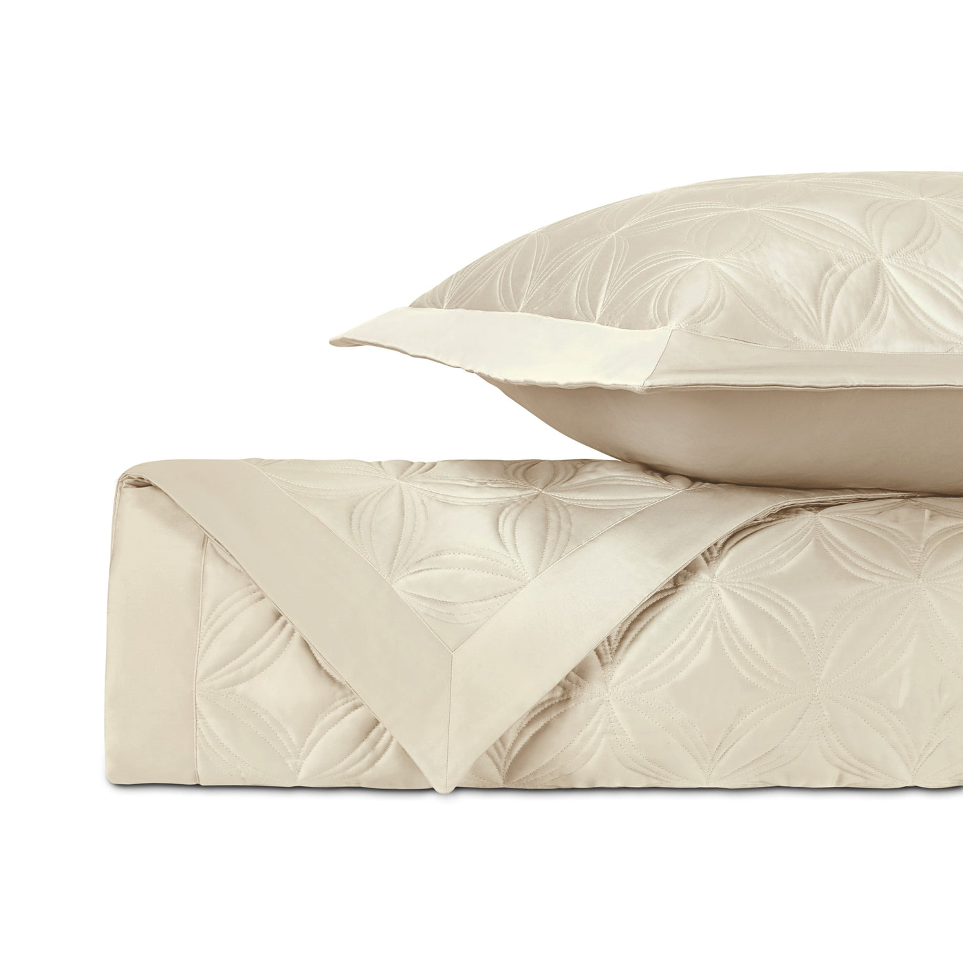 Ivory quilted coverlet folded with sham, showing embossed floral medallion pattern.