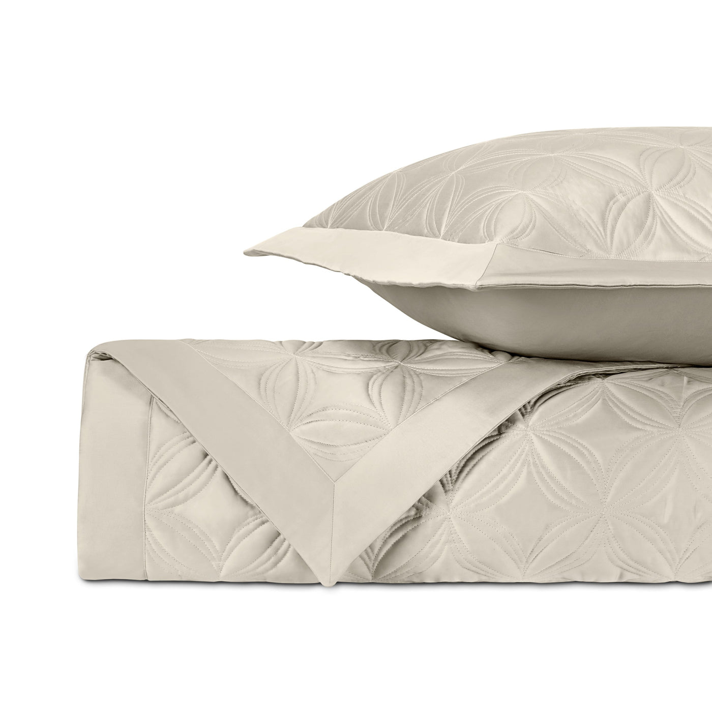 Close-up of ivory quilted coverlet with embossed floral medallion pattern and matching euro sham.