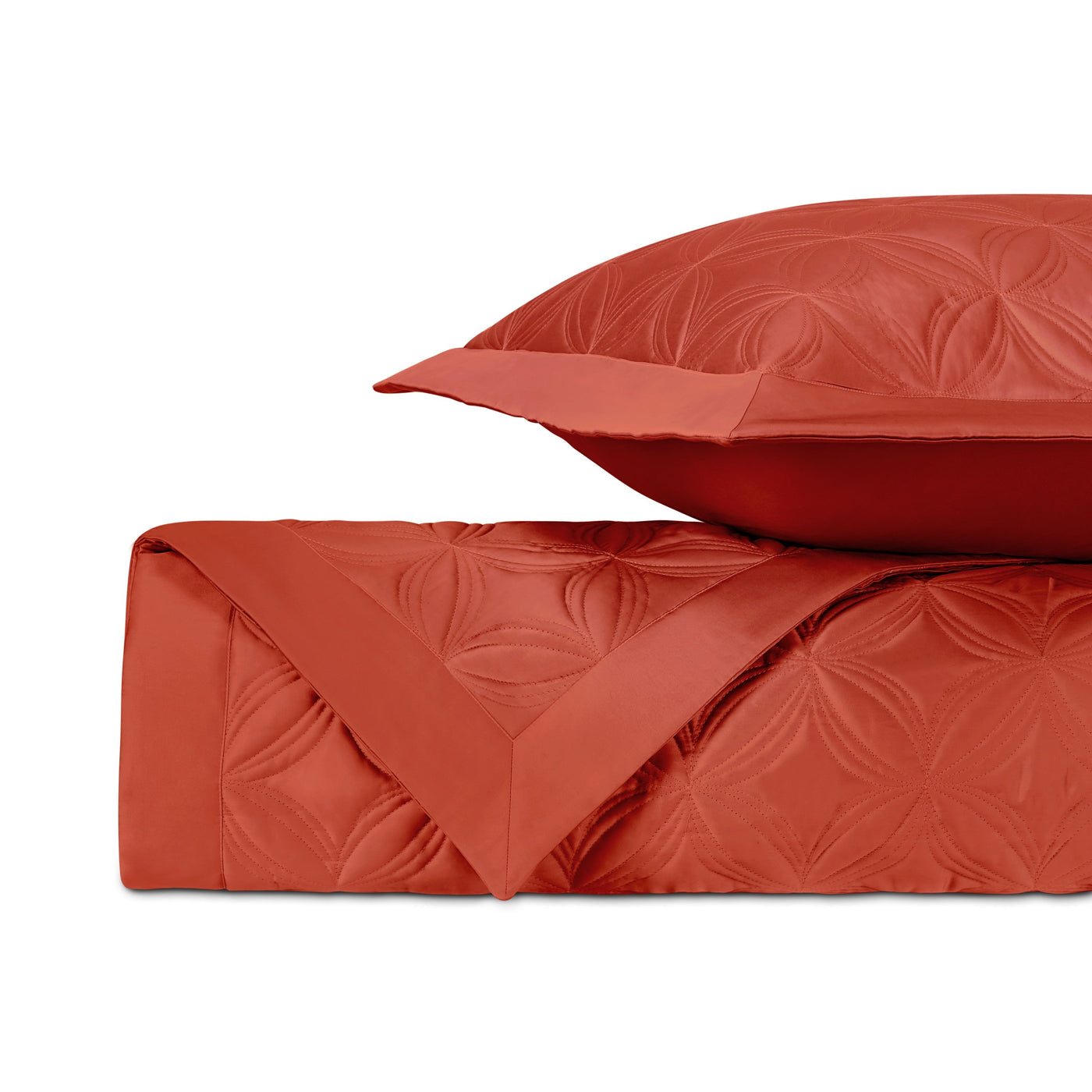 Close-up of vermillion quilted coverlet and sham with embossed floral medallion pattern.