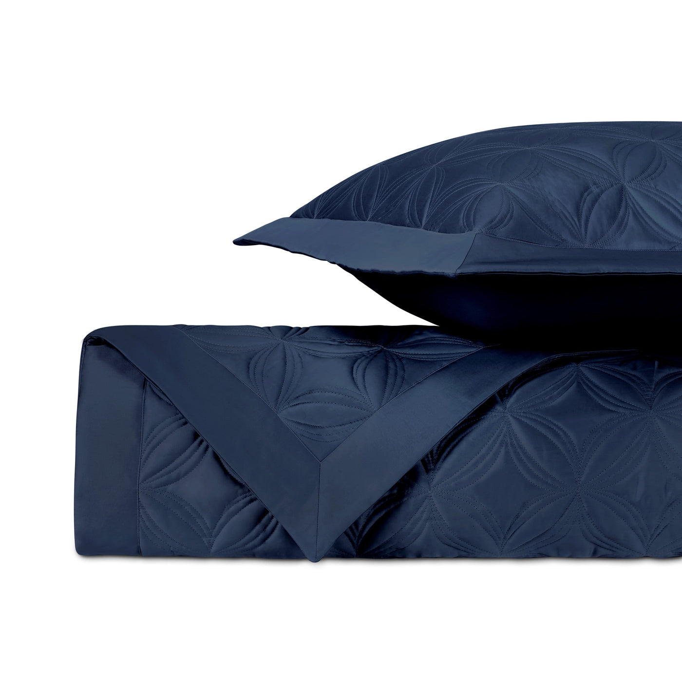 Close-up of navy quilted coverlet with tone-on-tone floral motif and matching euro sham.