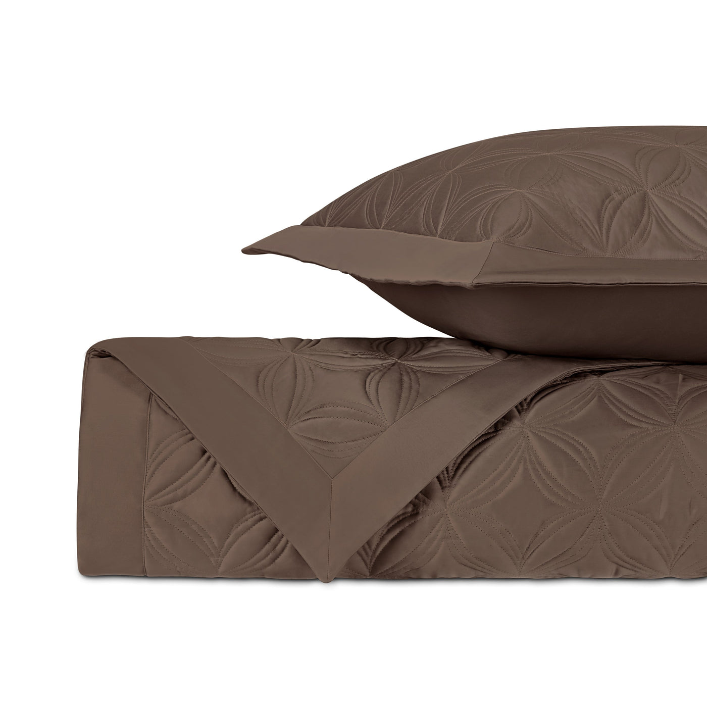 Close-up of mocha quilted coverlet showing embossed floral stitch pattern and folded edge.