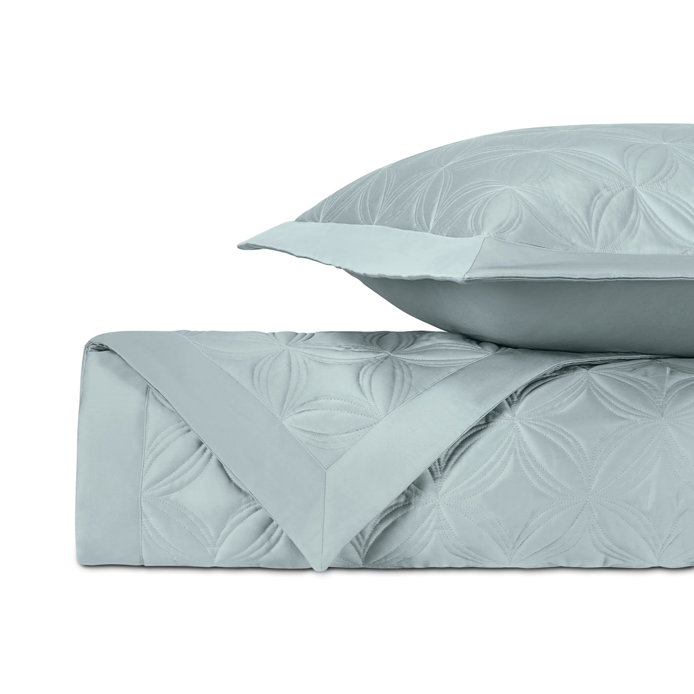 Folded mist blue quilted coverlet with embossed floral pattern and matching euro sham.