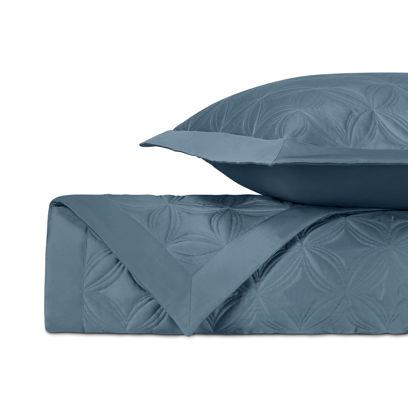 Folded slate blue quilted coverlet with floral medallion pattern and matching euro sham.