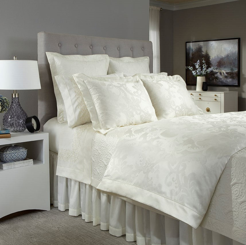Home Treasures Darian ivory damask bedding styled on a tufted bed.