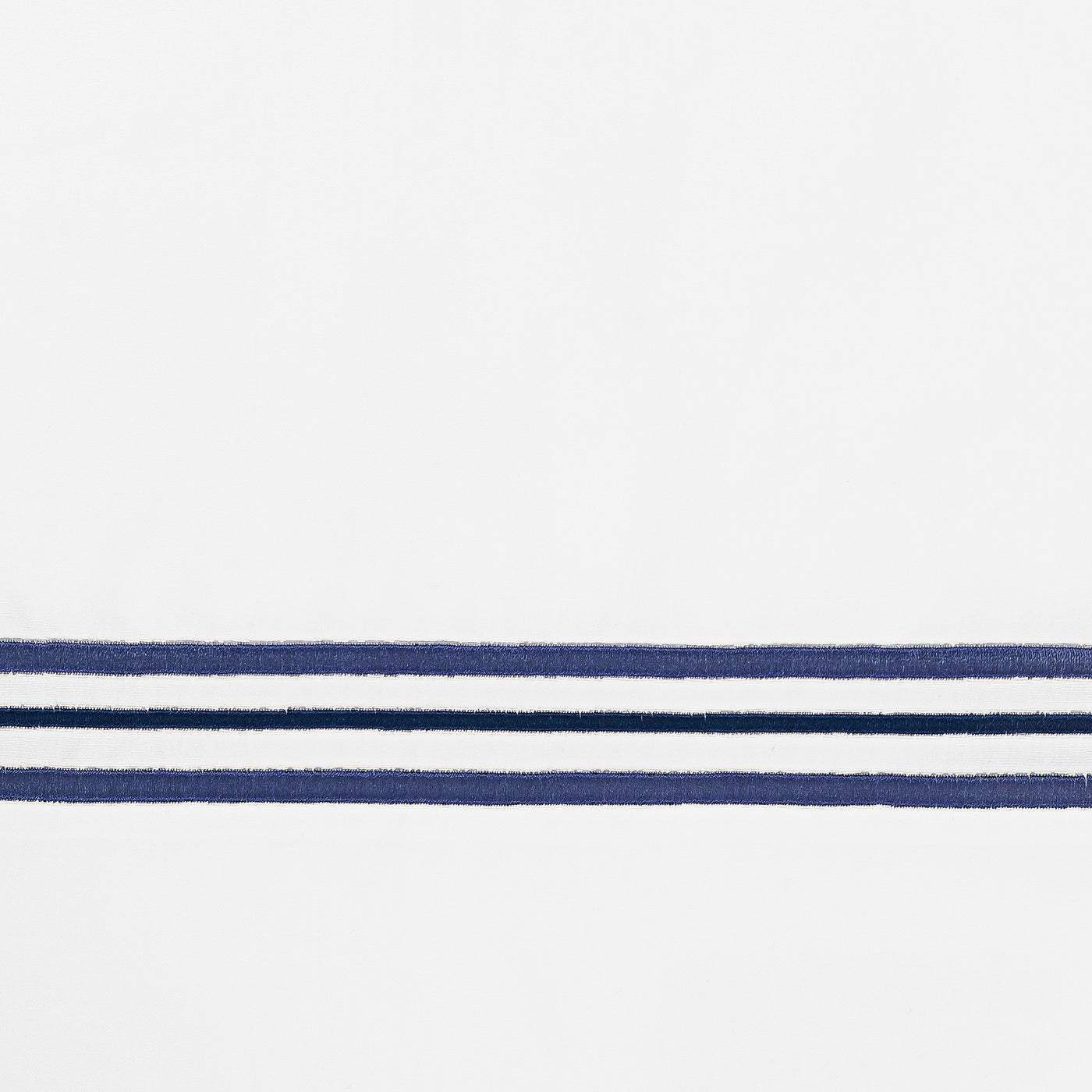 Close-up of navy blue embroidered triple-stripe border on white cotton fabric.