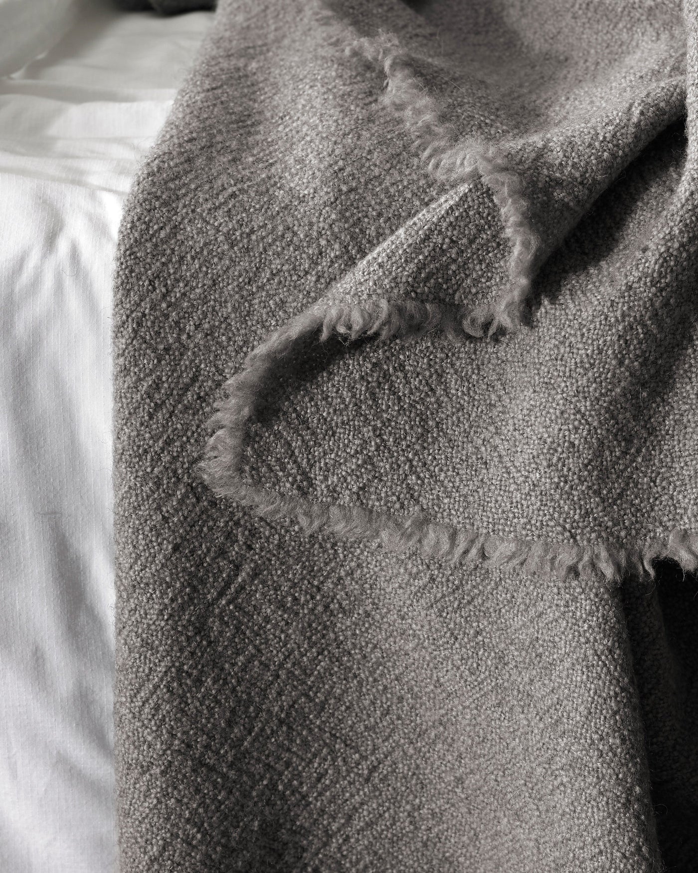 Close-up of Society Limonta Des blanket fringe edge in slate grey woven wool.