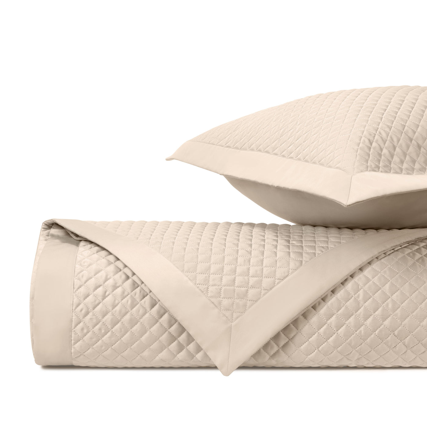 Close-up of ivory quilted diamond-pattern coverlet with sateen border trim.