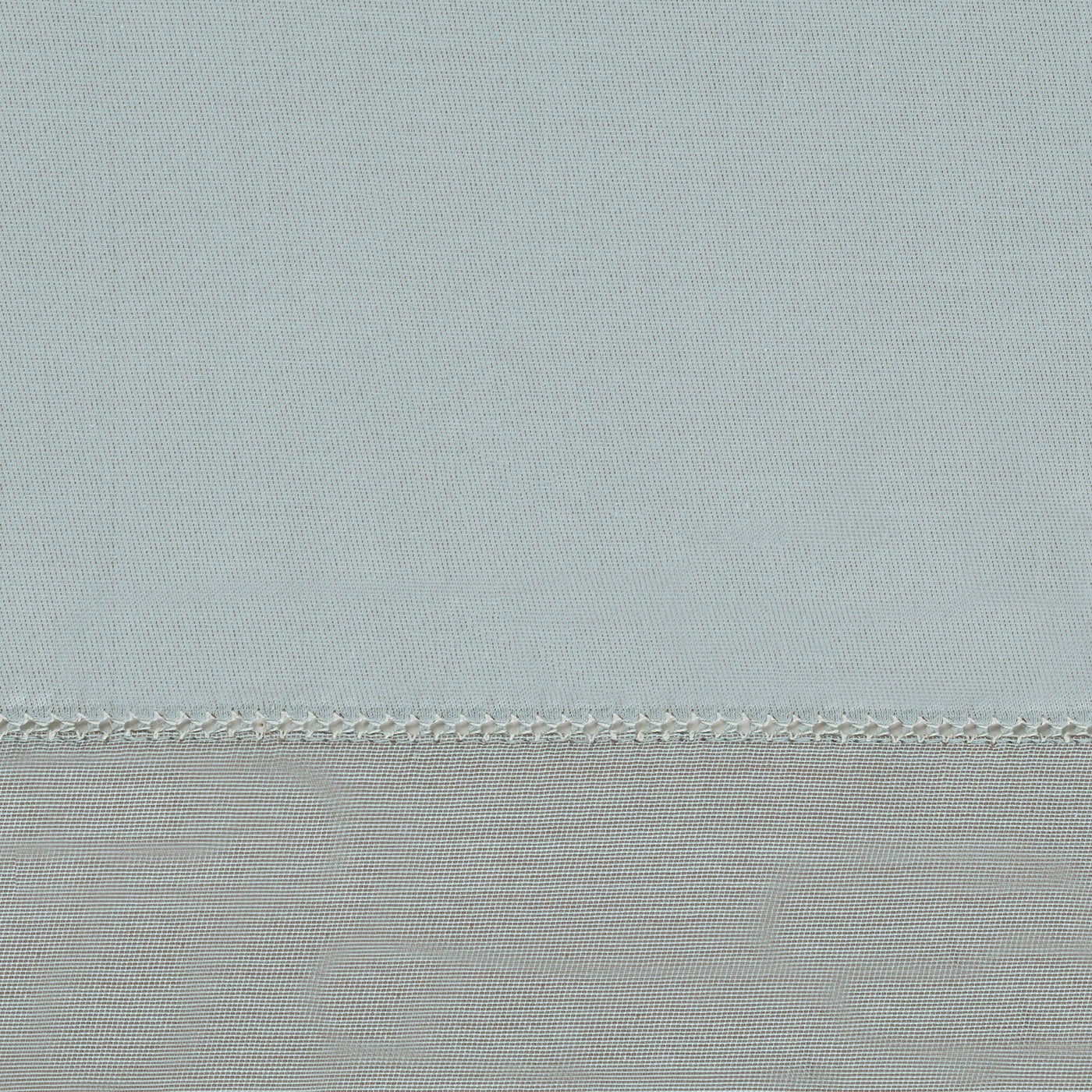 Close-up of pale aqua and silver-grey linen yardage with delicate chain-stitch border seam.