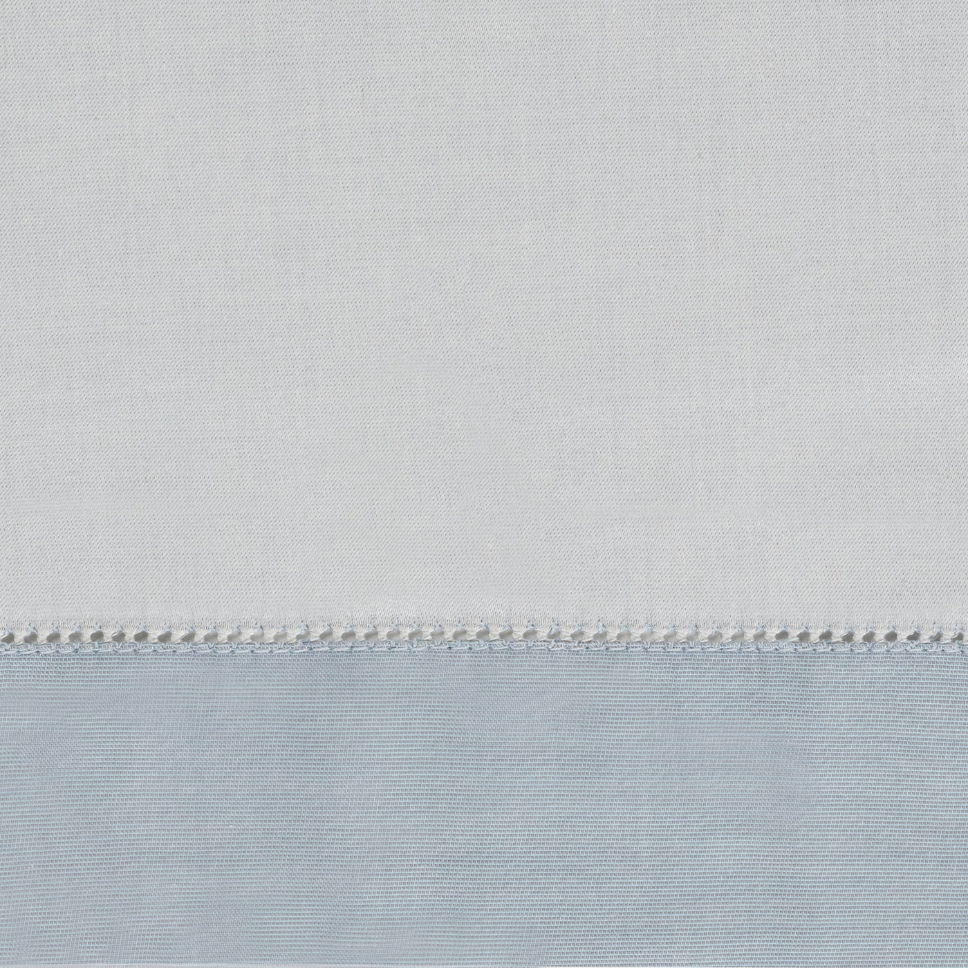 Close-up of ivory and powder blue cotton fabric with delicate hemstitch border detail.