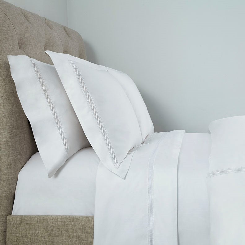 Home Treasures Doric white cotton bedding with embroidered border detail on linen headboard.