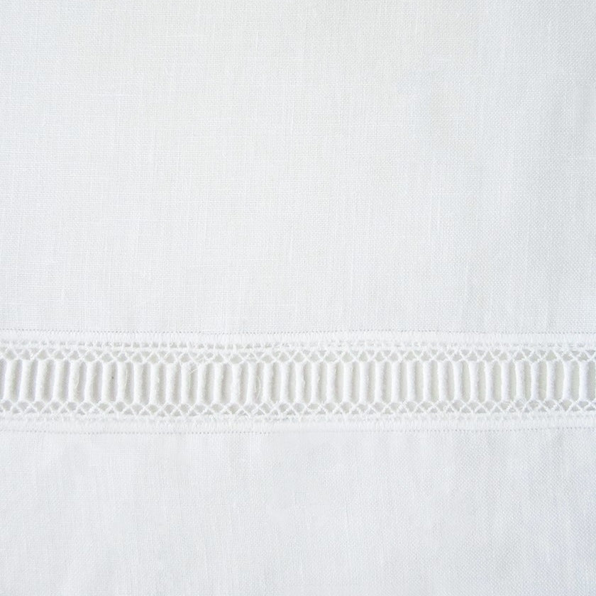 Close-up of ivory linen weave with delicate geometric lace trim border detail.