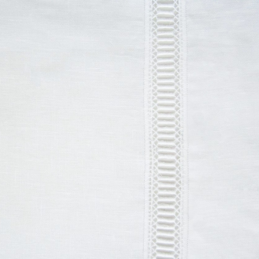 Close-up of ivory linen tablecloth with vertical geometric ladder lace trim detail.
