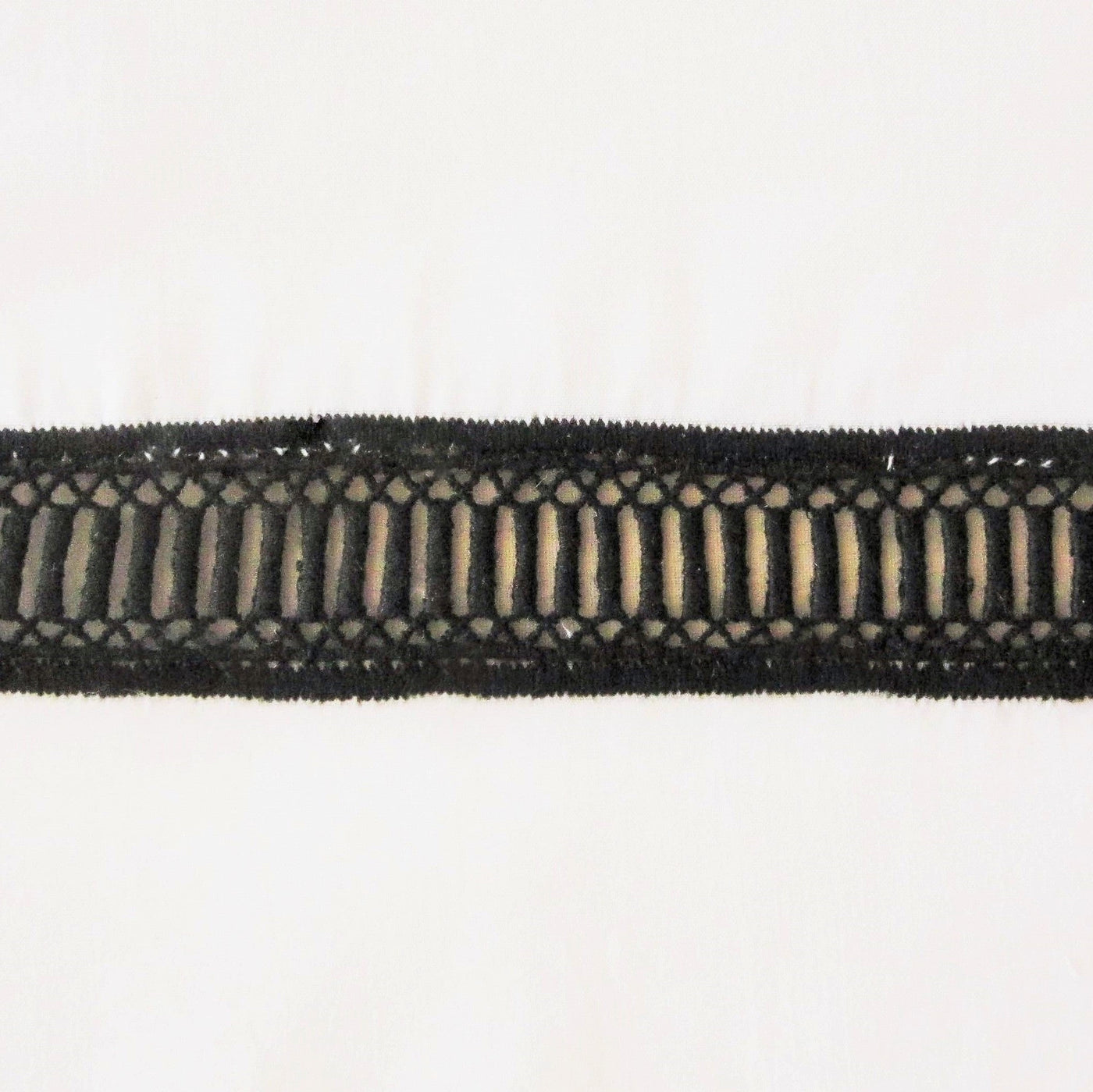 Close-up of black lace trim with open ladder weave detailing on ivory linen.