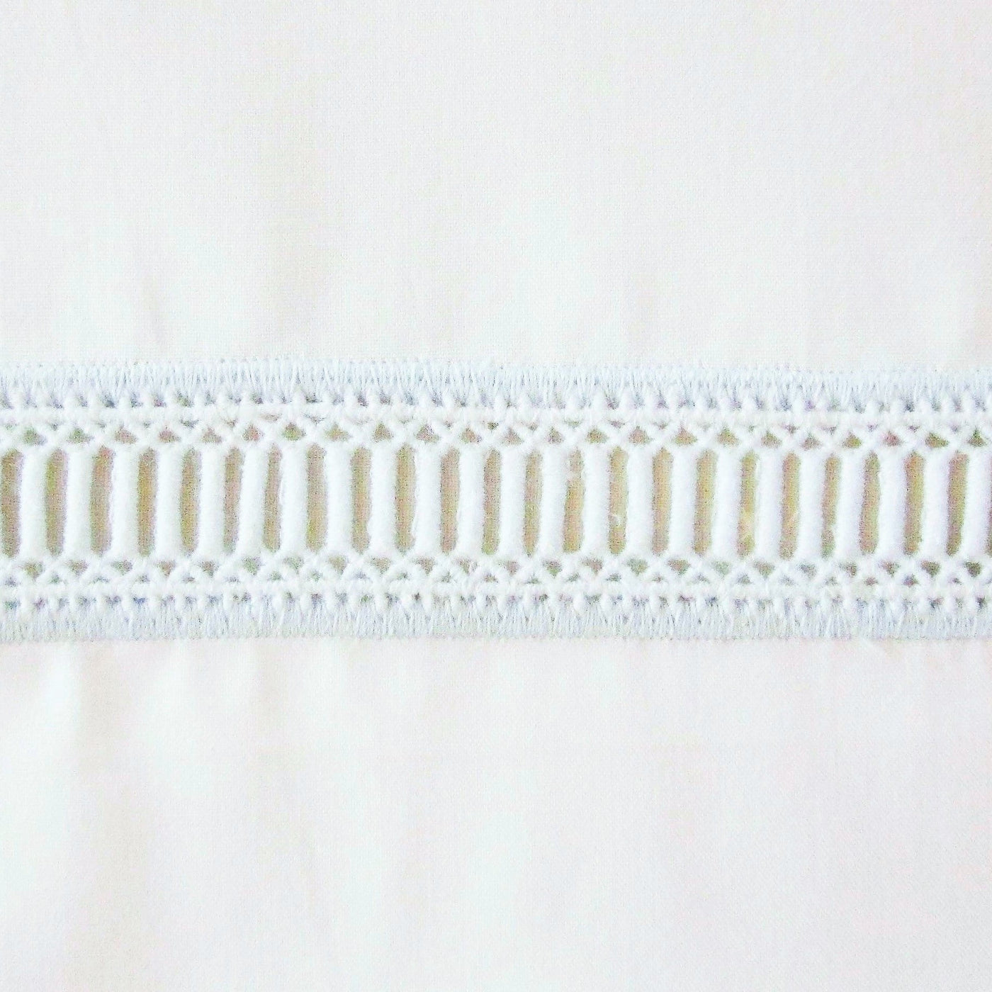 Close-up of Home Treasures Doric ivory cotton with geometric openwork lace trim border.