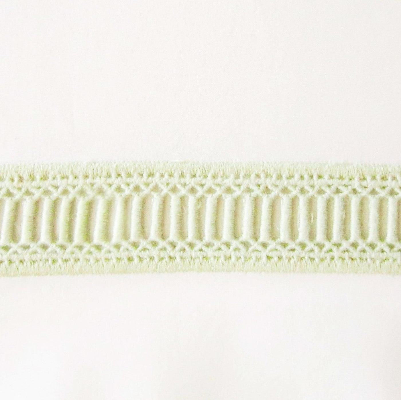 Close-up of Home Treasures Doric sage green woven lace trim detail.