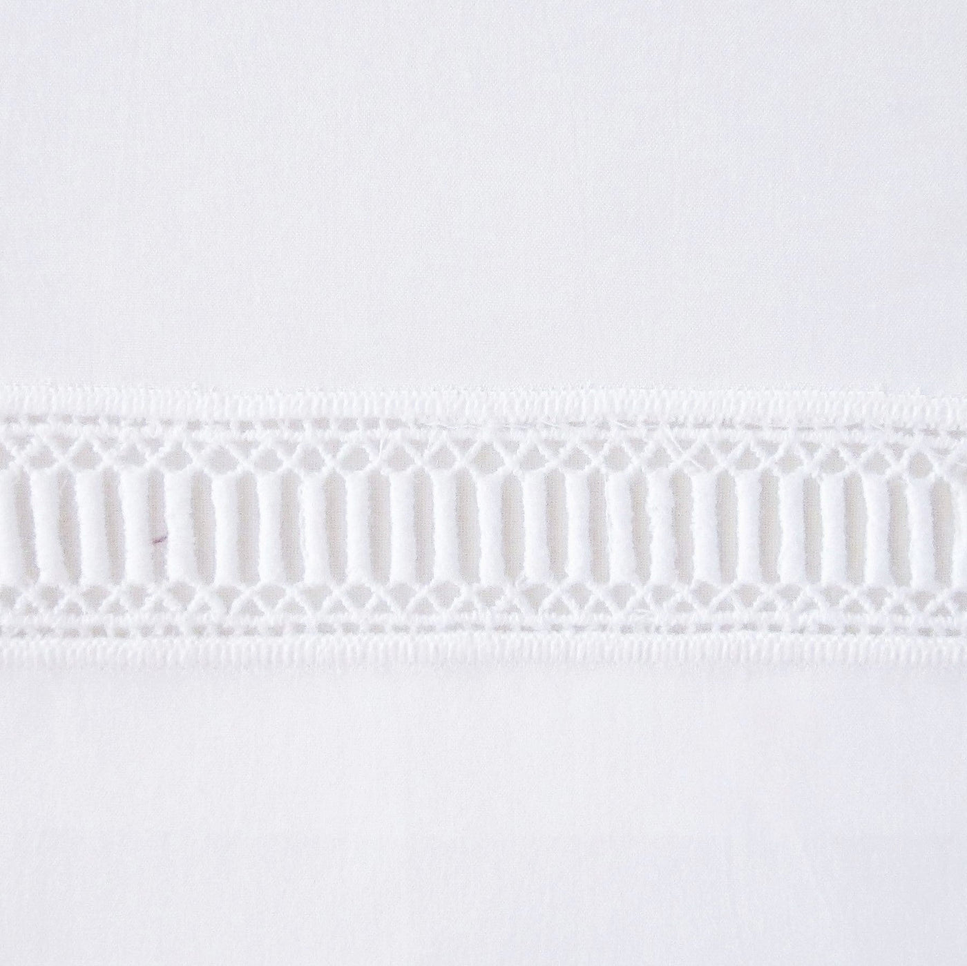 Close-up of white cotton fabric with a woven ladder lace border trim detail.
