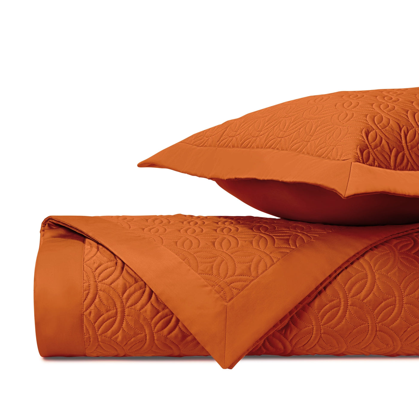 Tonal geometric quilted pattern detail on folded tangerine coverlet and sham.