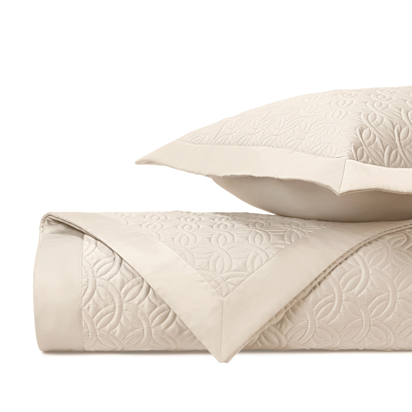 Close-up of ivory quilted cotton with geometric floral embroidered pattern and satin border trim.