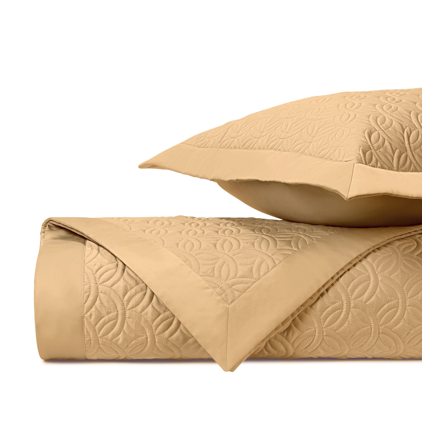 Honey gold quilted coverlet folded with matching sham, geometric tonal stitching visible.