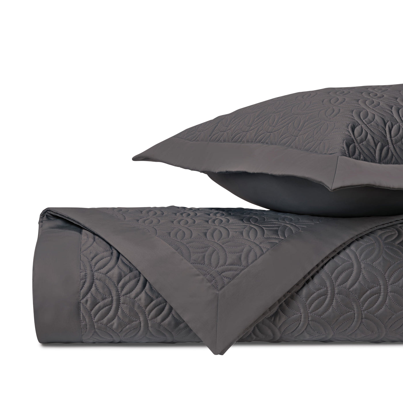 Charcoal quilted coverlet folded with matching sham, showing geometric medallion stitching detail.
